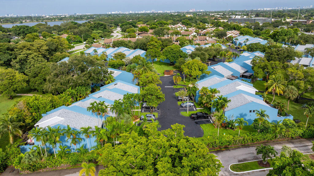 Aerial view of a blue-roofed residential community with palm trees and a distant skyline.