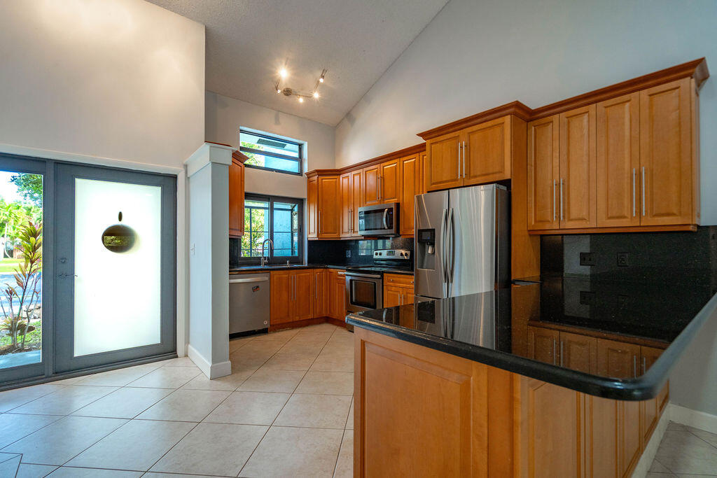 Kitchen with tall wood cabinets, stainless steel appliances, and a large black-countertop peninsula.