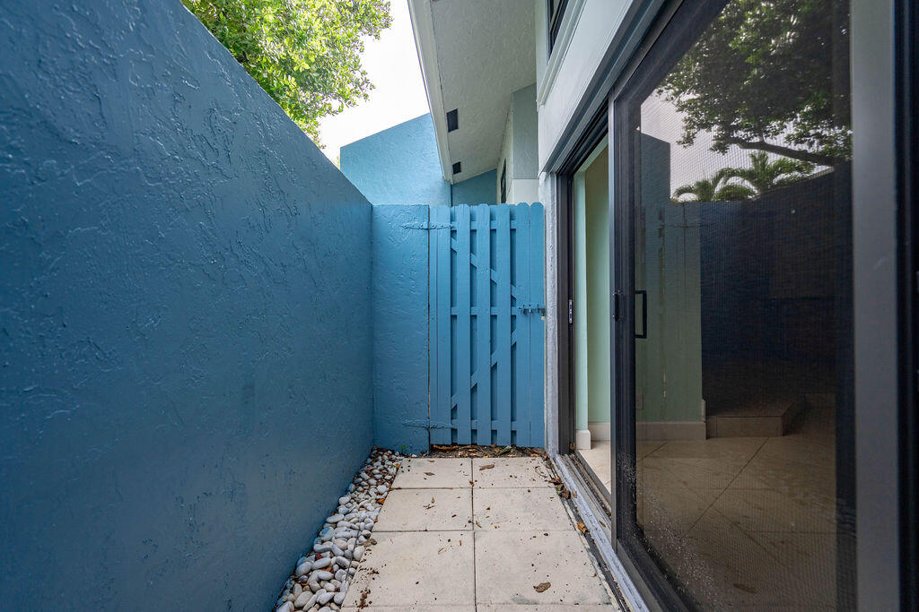 Narrow tiled patio with blue privacy walls, a matching gate, and sliding glass door.