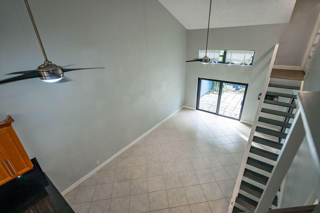 Double-height living room with tile floors, a staircase, and sliding doors to a patio.