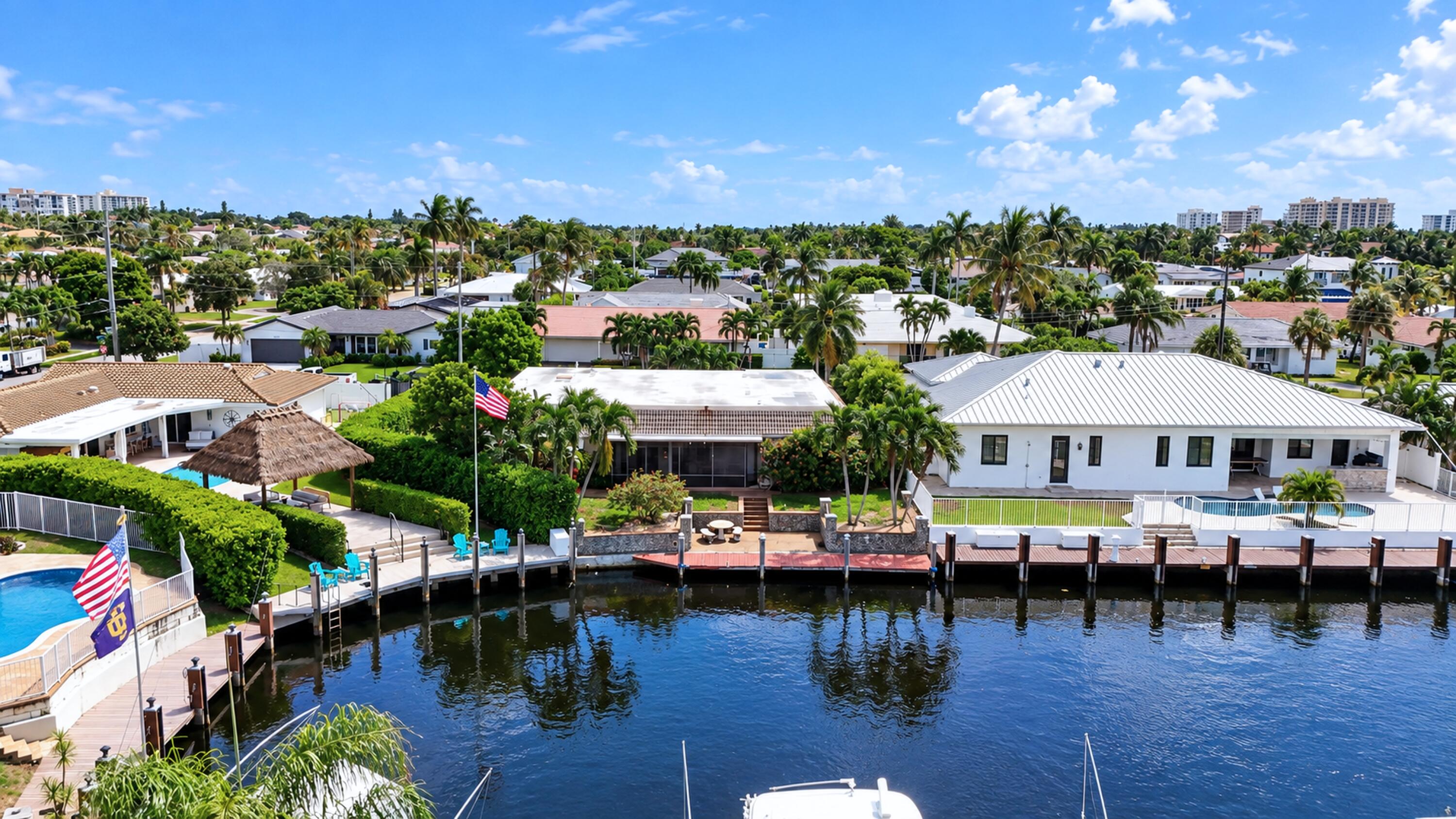 Aerial view of canal-front homes with private docks, palm trees, and a backyard pool.