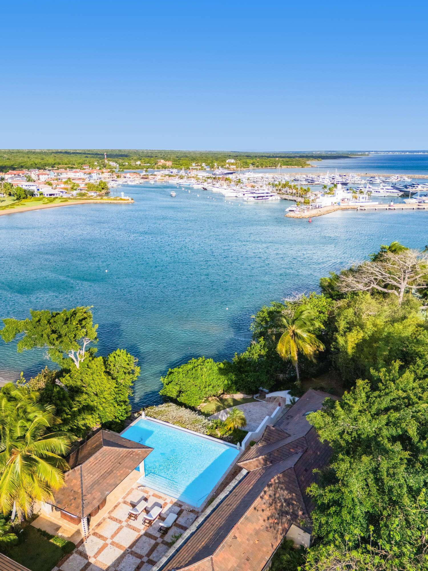 Villa pool overlooking a yacht-filled harbor, framed by tropical greenery.