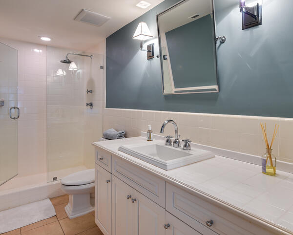 Bathroom with a white vanity and sink, teal accent wall, and glass-enclosed tiled shower.