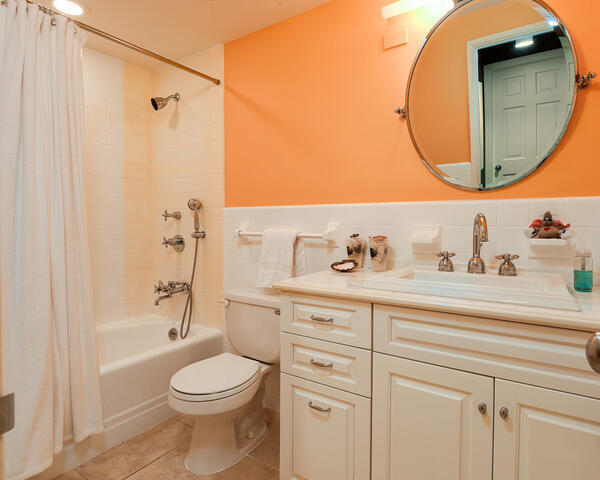 Bathroom with a cream vanity, round mirror, and curtained bathtub.