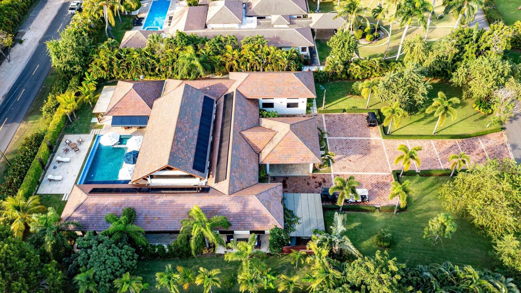 Aerial view of 1 Los Mangos with a swimming pool, tiled roof, and palm-lined grounds.