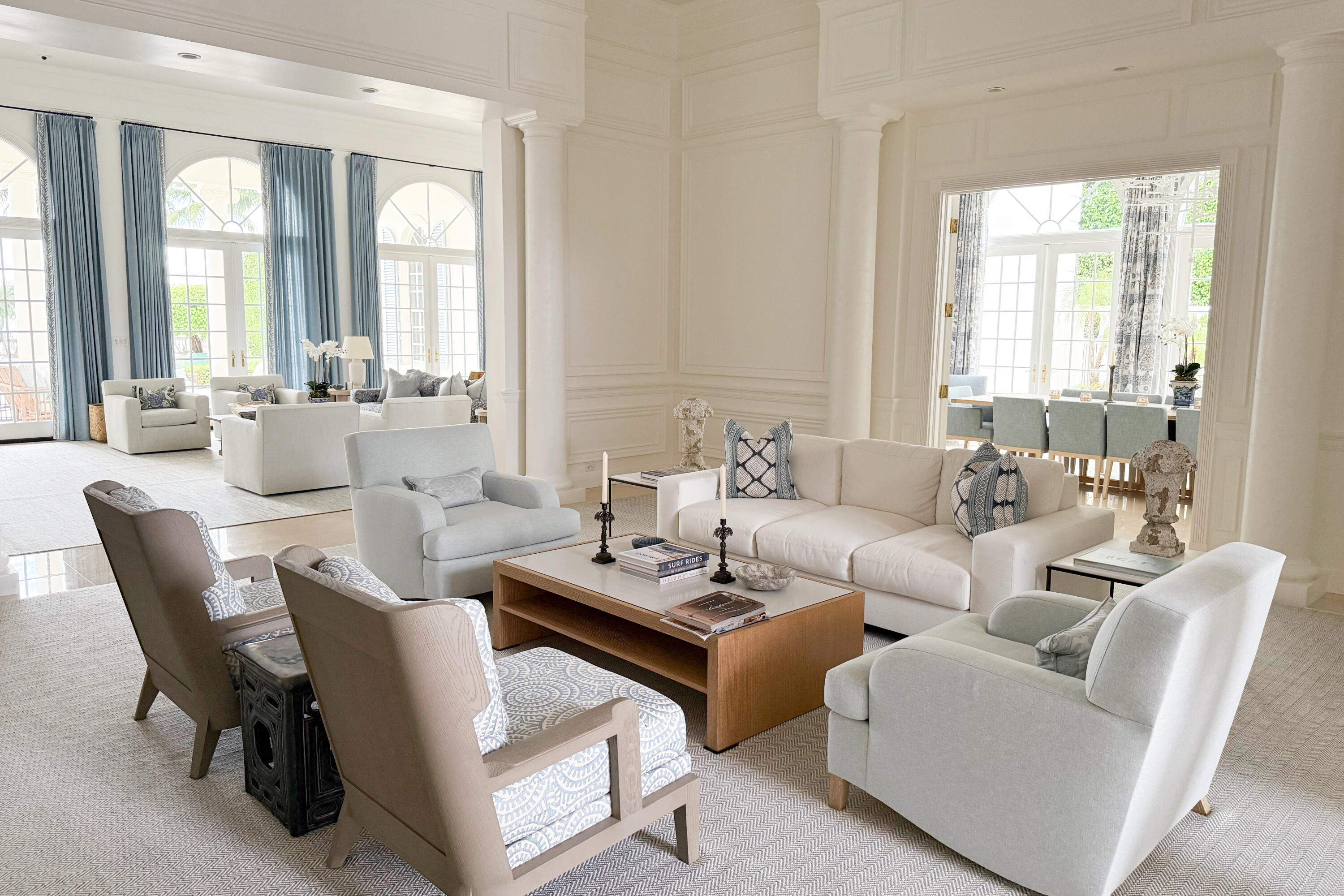 Furnished living room with white seating, tall arched windows, and blue curtains.