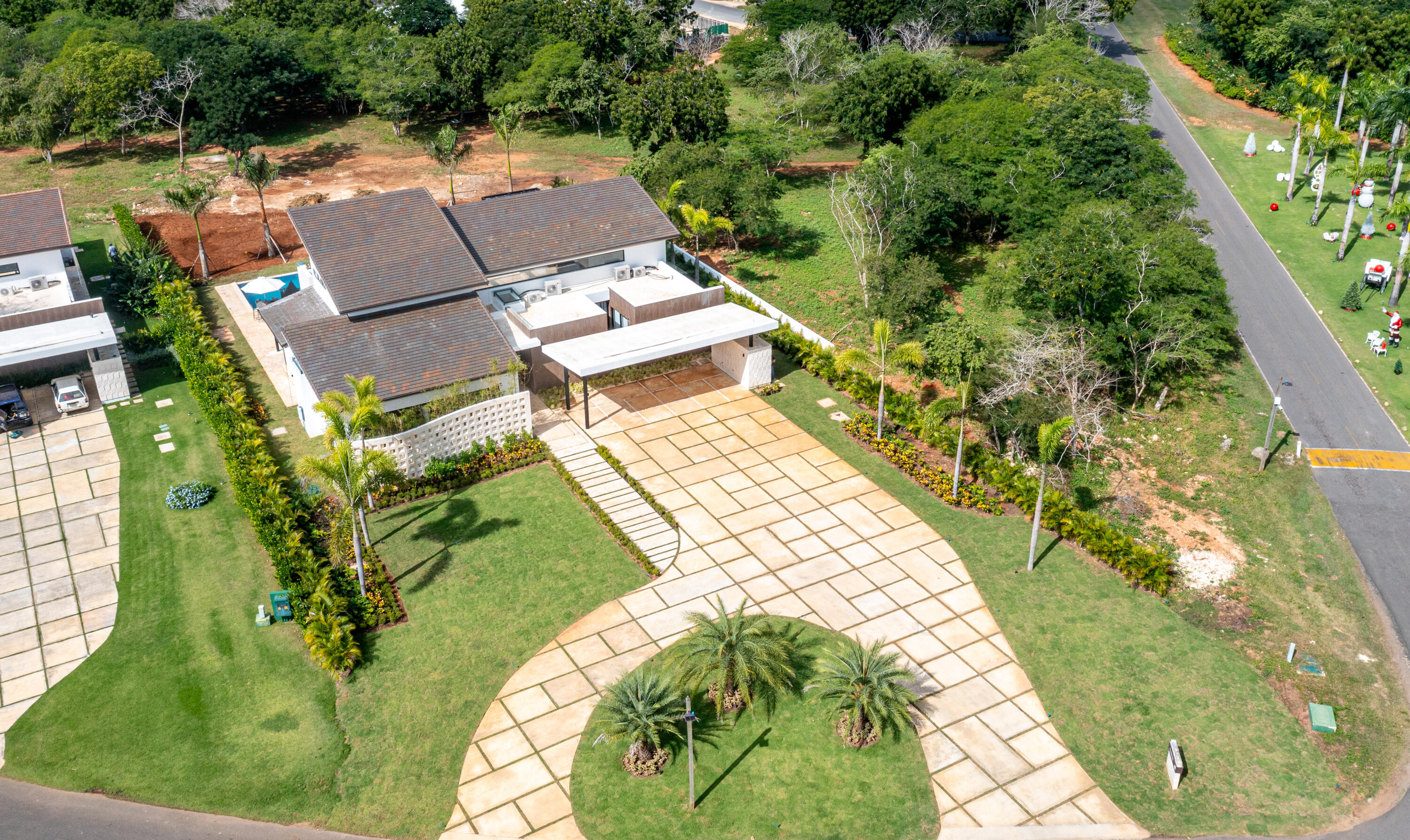 Modern home with dark tiled roofs and a sweeping stone driveway, viewed from above.