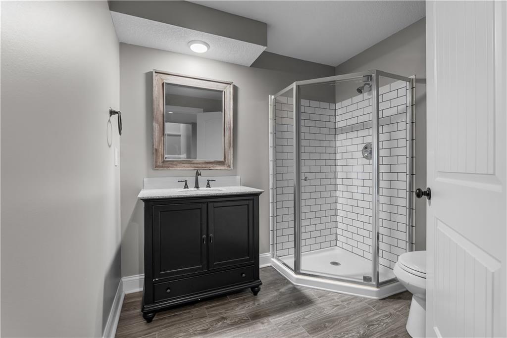 Bathroom with a dark vanity and glass corner shower lined with white subway tile.