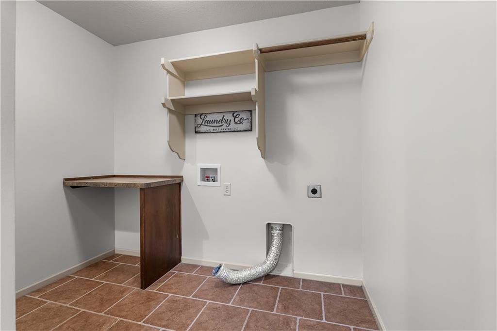 Laundry room with wall shelves, a small counter, and washer and dryer hookups.