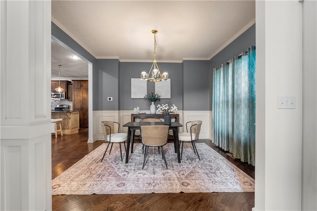Dining room with a dark table, woven chairs, patterned rug, and teal curtains.