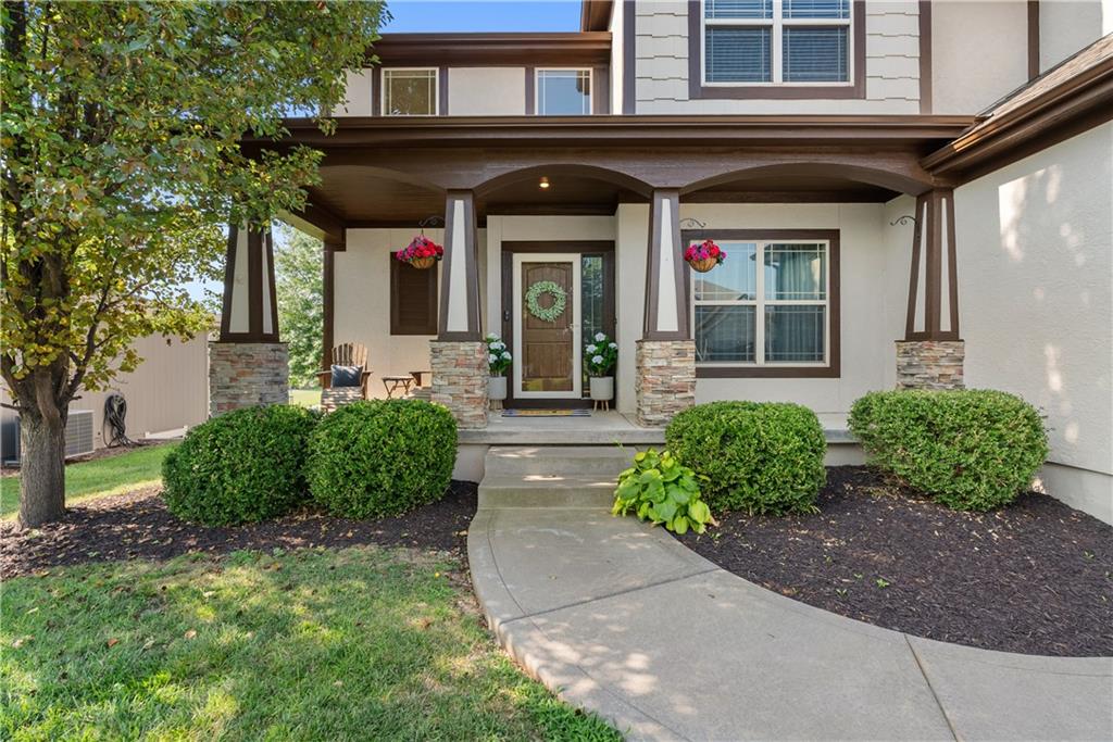 Home entrance with a covered porch, stone column bases, and a curved walkway.
