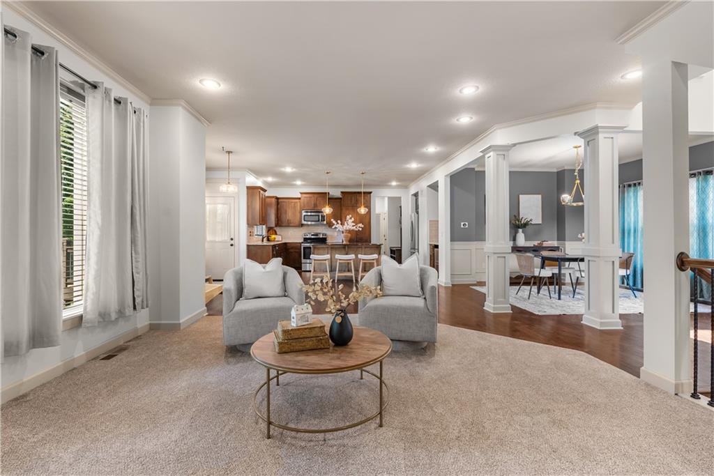 Open-plan living room with a round coffee table, adjoining a kitchen and dining area.