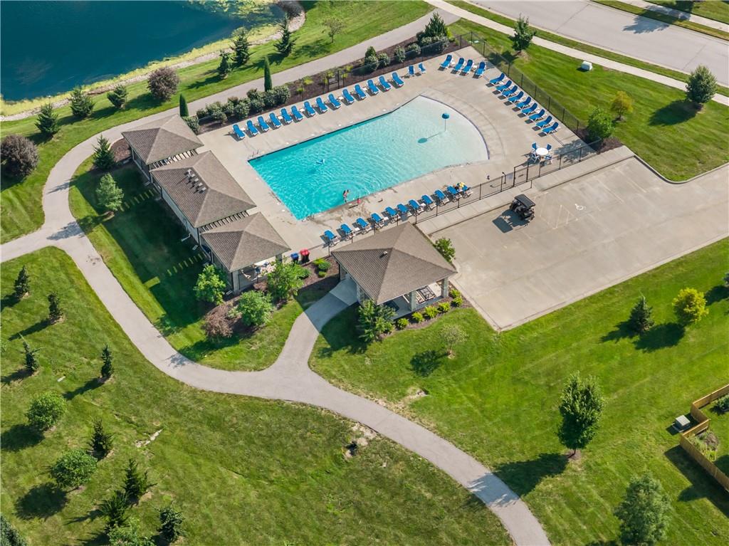 Aerial view of a community pool beside a lake, with blue loungers and pavilion.