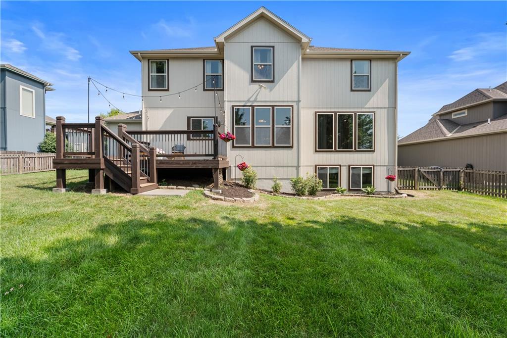 Rear of a two-story house with a raised wooden deck and broad lawn.
