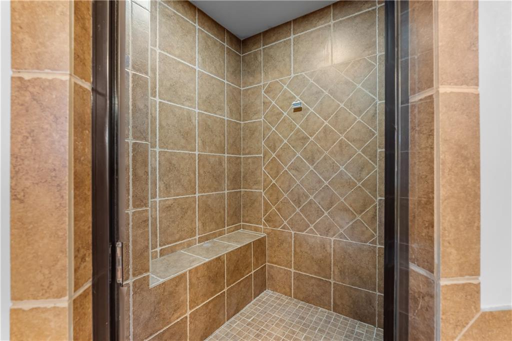 Walk-in shower with tan tile, a built-in bench, and a small square-tile floor.
