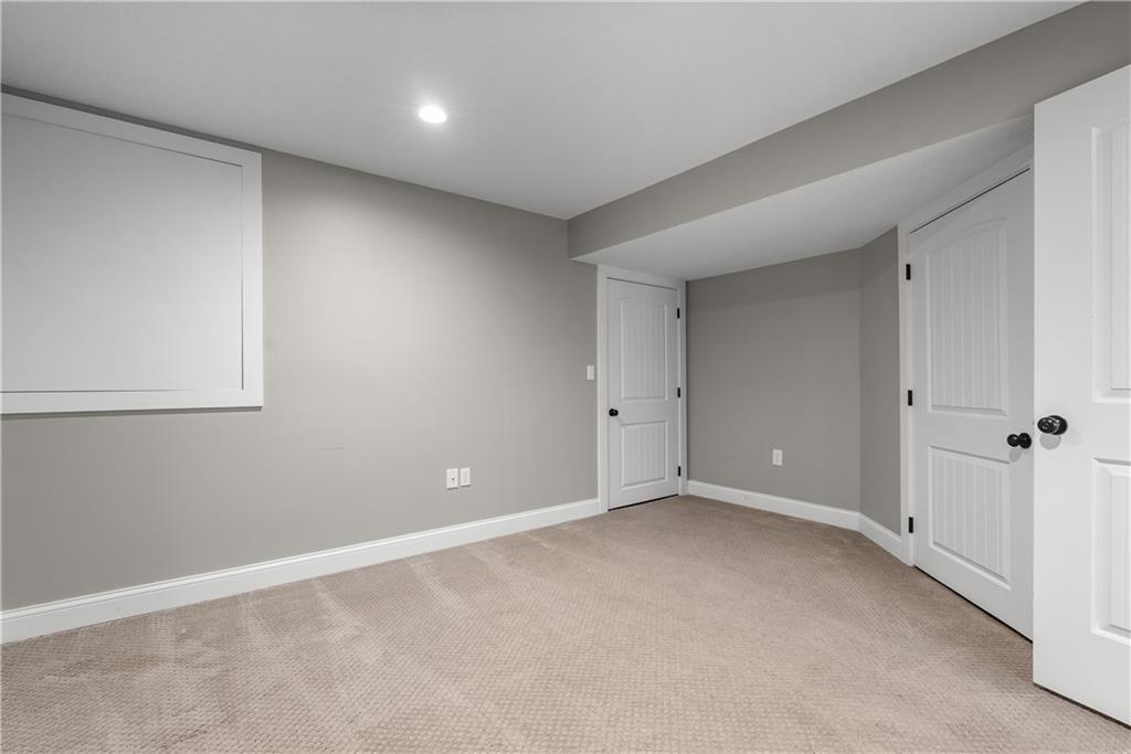 Empty carpeted room with gray walls and several white paneled doors.
