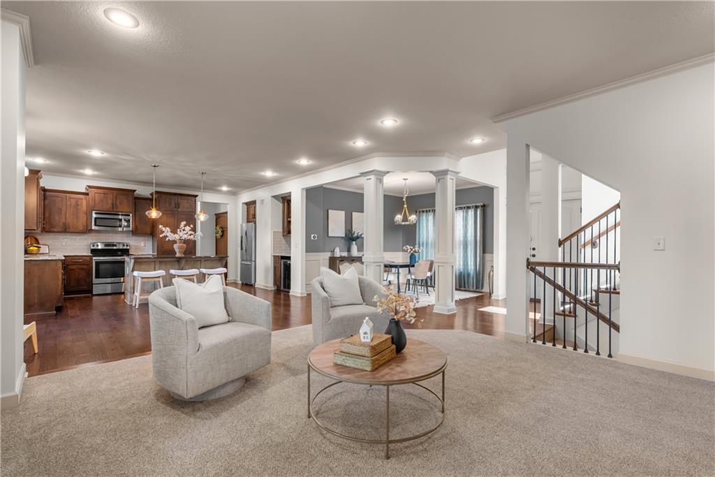 Open-plan living room with gray armchairs, adjoining a dark wood kitchen and dining area.