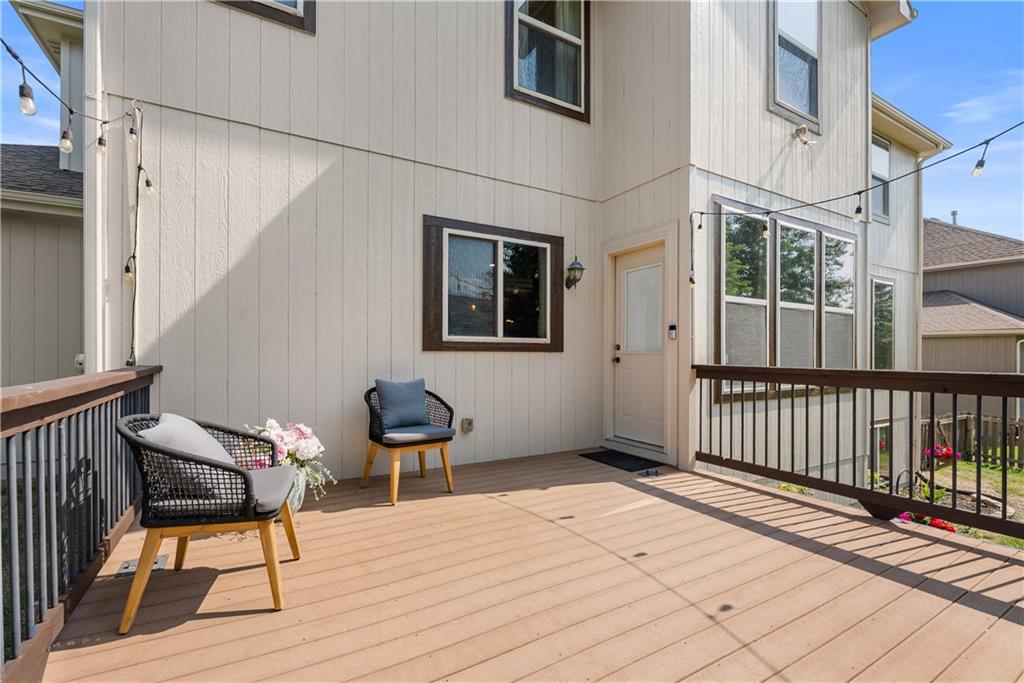 Raised deck with dark railings, two chairs, and a light-colored home exterior.
