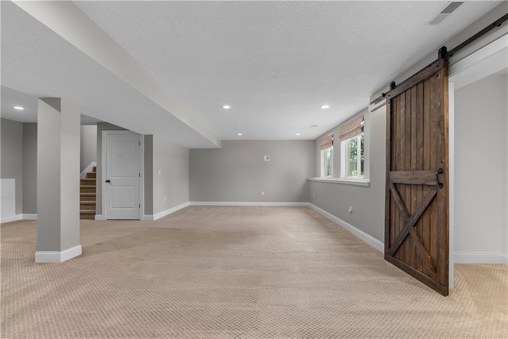 Finished basement with beige carpet, small windows, and a rustic sliding barn door.