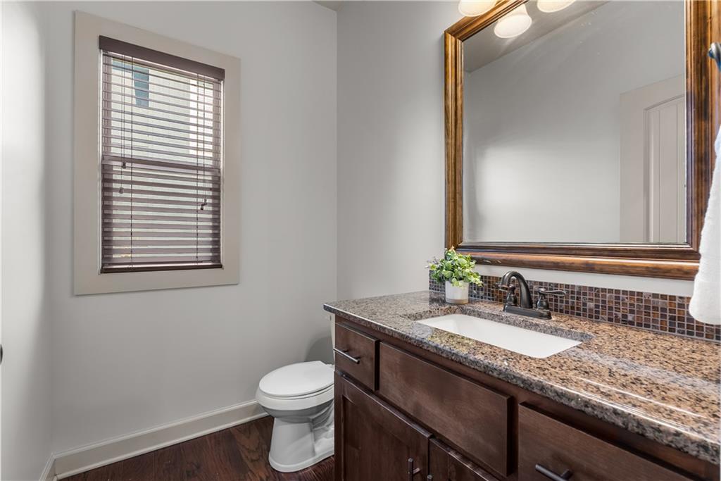 Bathroom with a dark wood vanity, granite counter, mosaic backsplash, and large framed mirror.