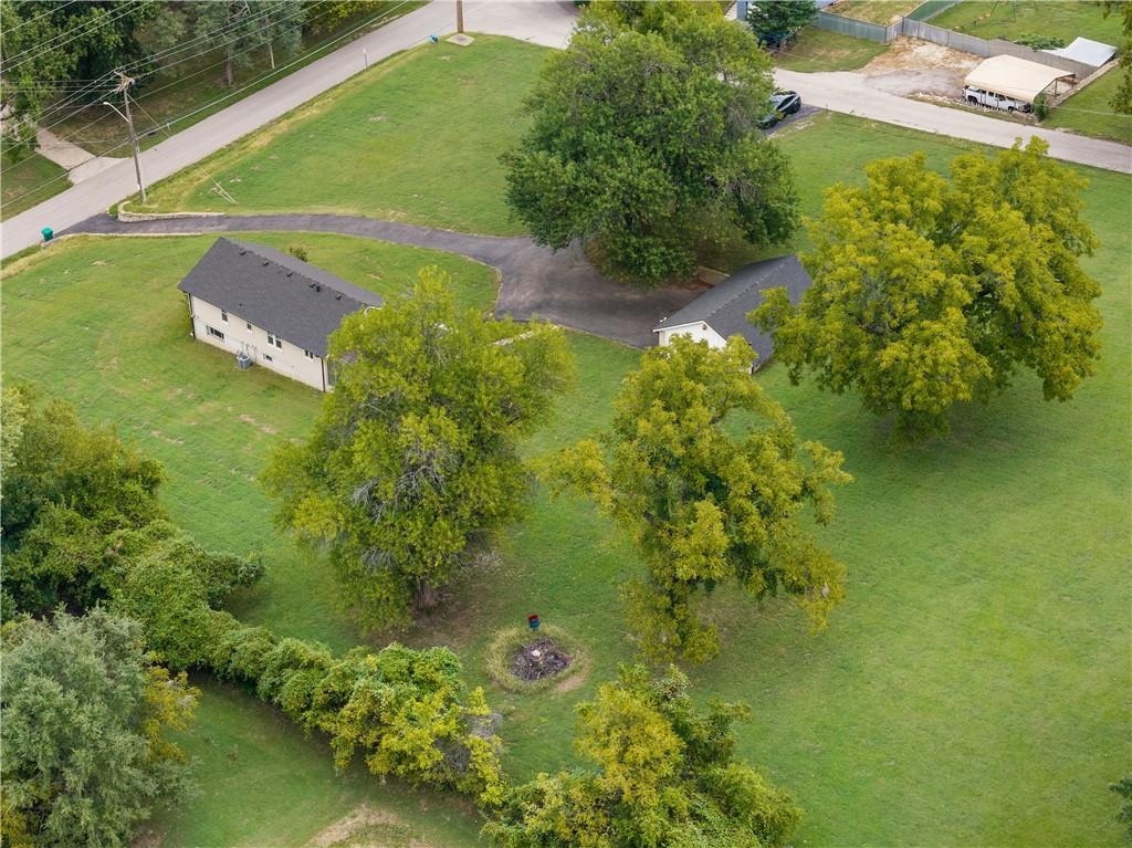 Aerial view of two homes amid mature trees and expansive lawns, with a curved driveway.
