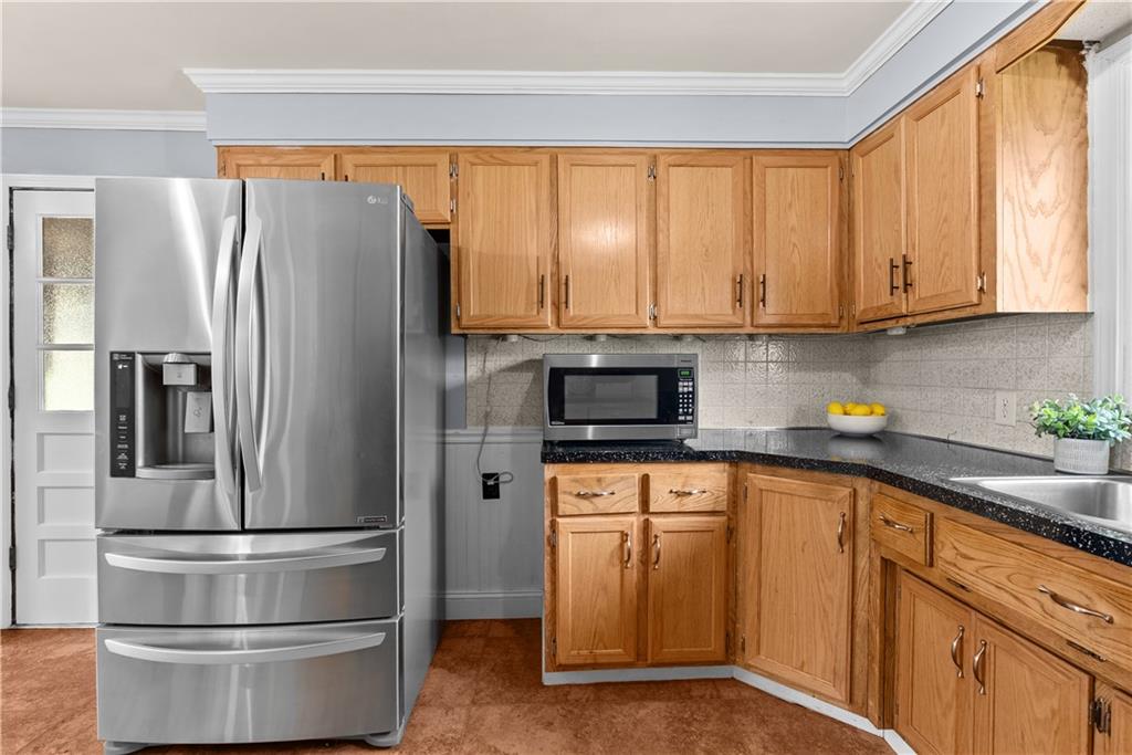Kitchen with wood cabinets, dark countertops, and a stainless steel French-door refrigerator.