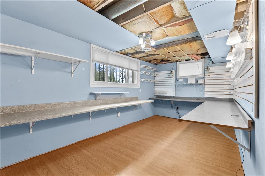 Empty room with wall-mounted display shelves, long counters, and exposed ceiling insulation.
