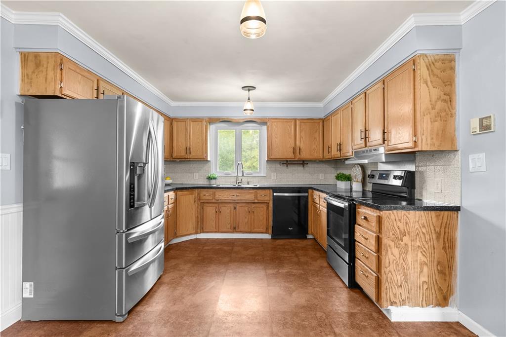 Kitchen with honey-colored cabinets, stainless steel appliances, and a window above the sink.
