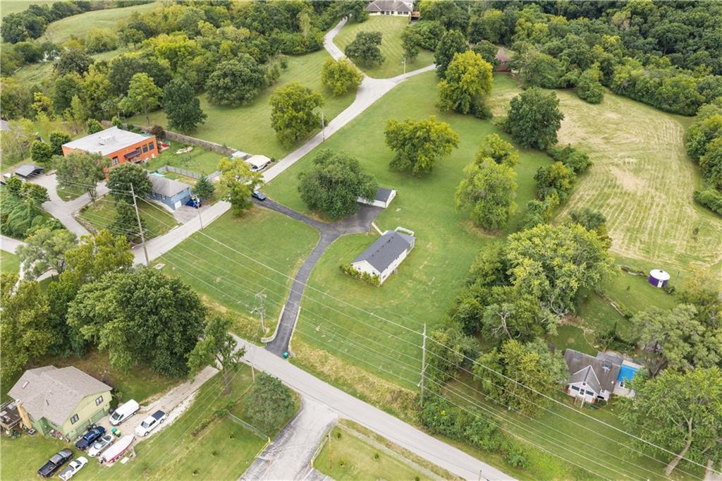 Aerial view of a property with a red building and outbuildings amid lawns and trees.