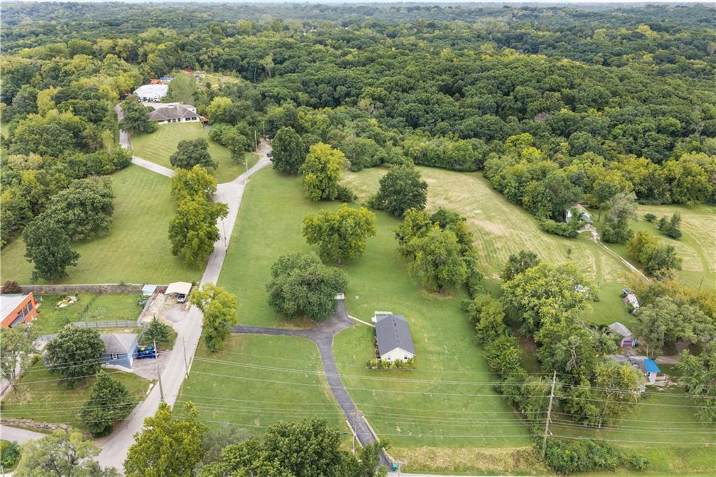 Aerial view of a house on a large green property beside dense woodland.