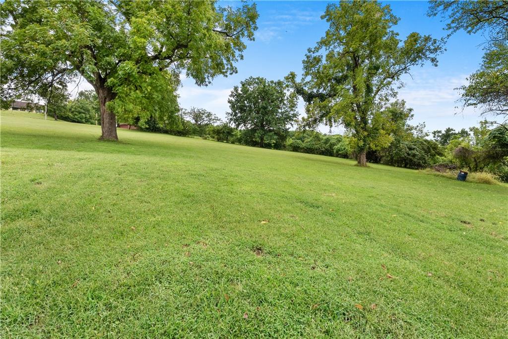 Grassy property grounds with mature trees and a gently sloping lawn.