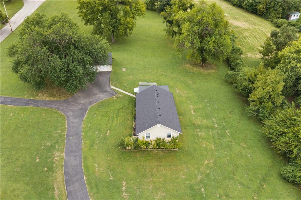 Aerial view of a single-story house on a large grassy lot, surrounded by mature trees.