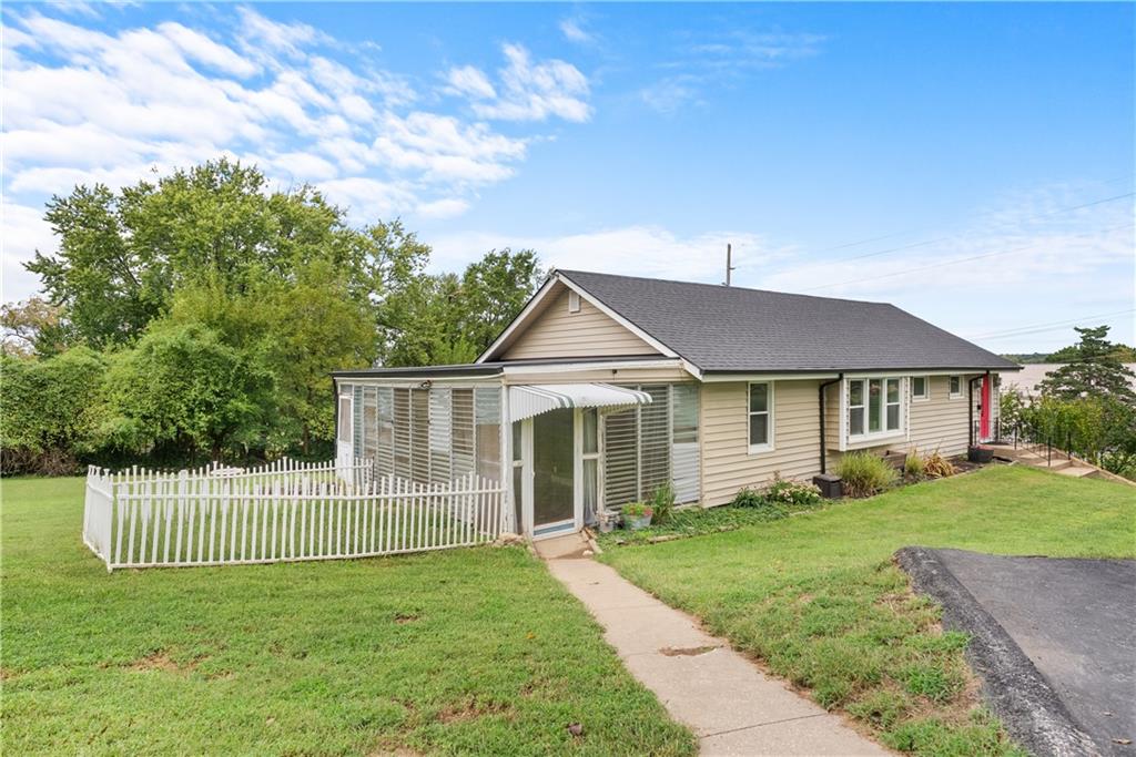 Single-story beige house with a screened porch and white picket fence.