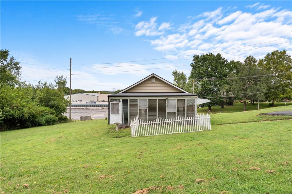 Gray house with a screened porch and white picket fence on a broad lawn.