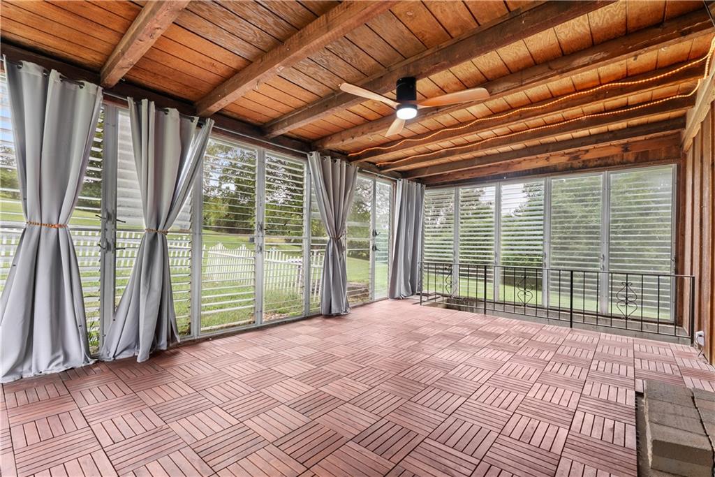 Sunroom with a wood-plank ceiling, tiled floor, and windows overlooking a fenced lawn.