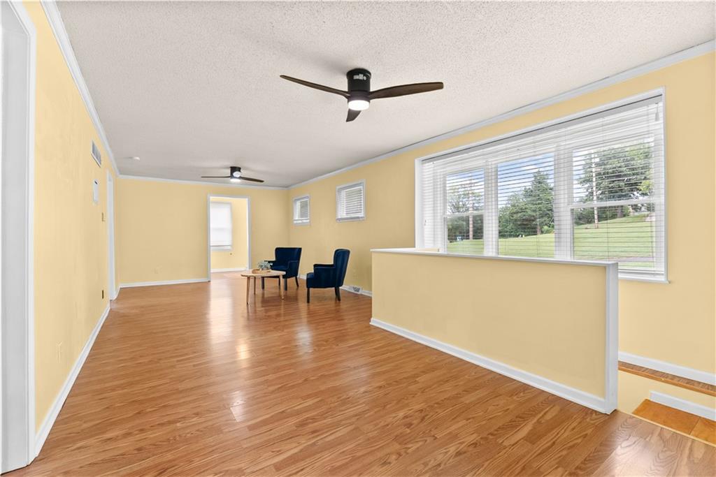 Bright room with yellow walls, wood floors, two blue chairs, and a large window overlooking a lawn.