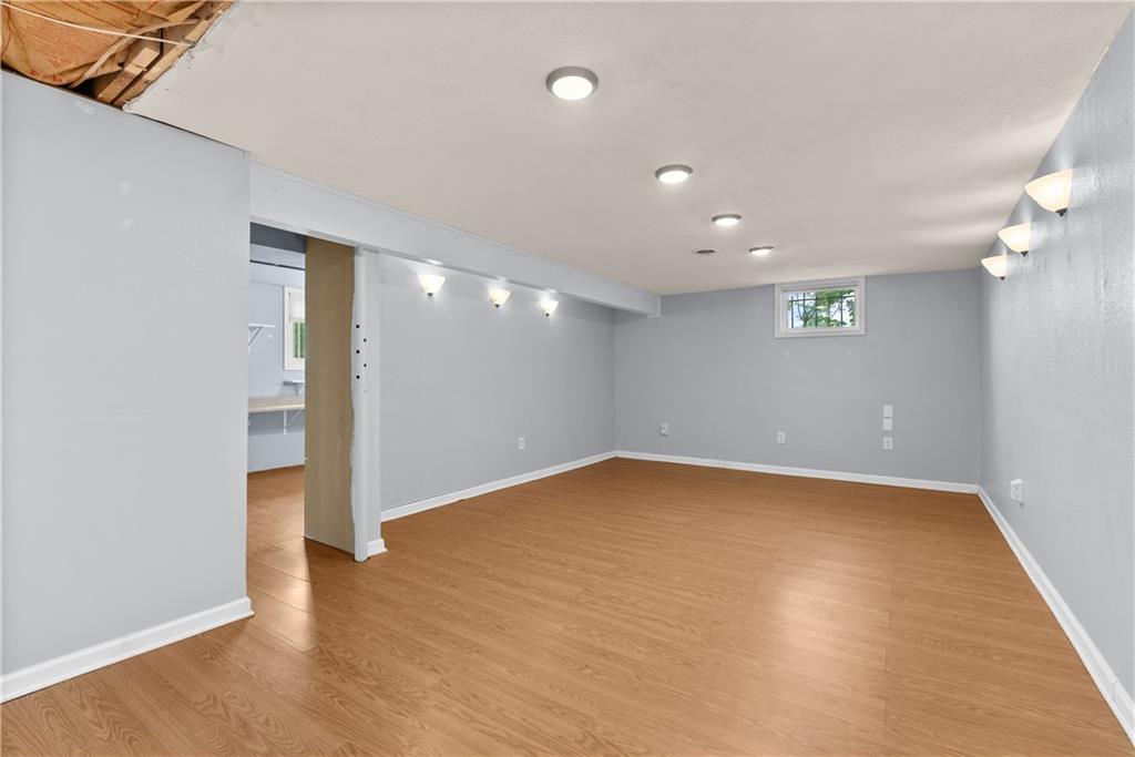 Finished basement room with wood-look flooring, gray walls, and recessed lights.