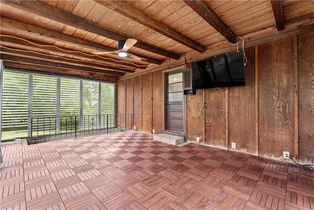 Wood-paneled sunroom with patterned tile flooring and sliding glass doors overlooking greenery.
