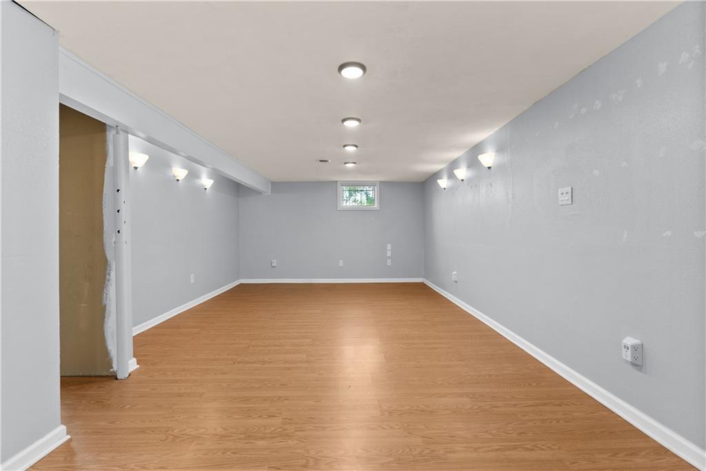 Empty finished room with wood-look flooring, recessed lights, and a small high window.