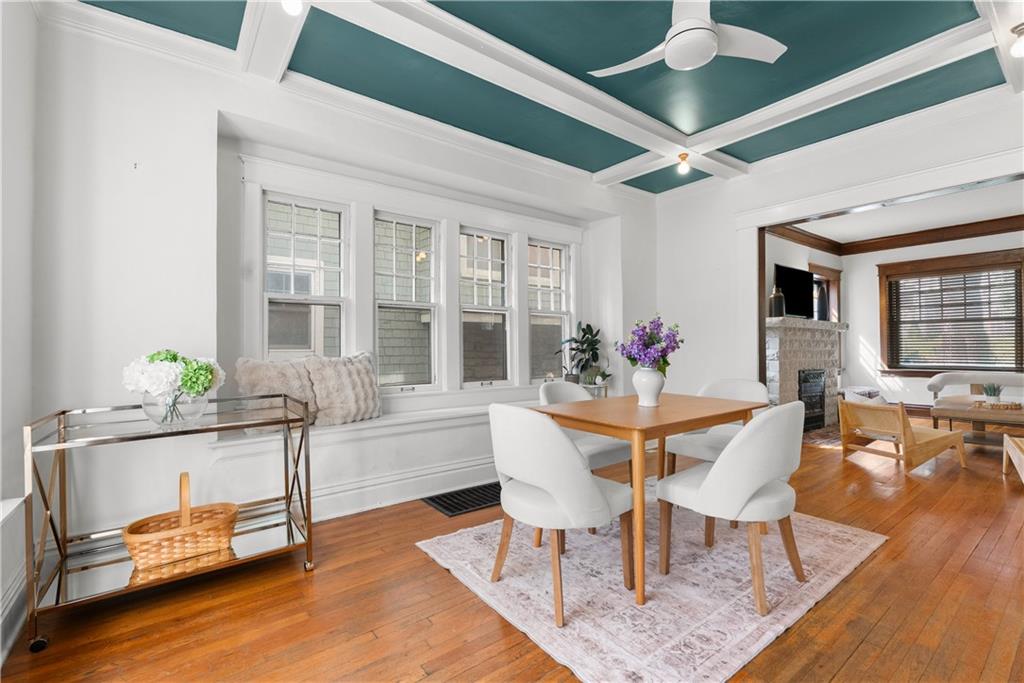 Dining room with a teal coffered ceiling, window bench, hardwood floors, and adjoining living room.