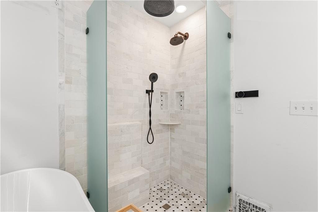 Walk-in shower with frosted glass panels, white tile, mosaic floor, rainfall showerhead, and built-in bench.