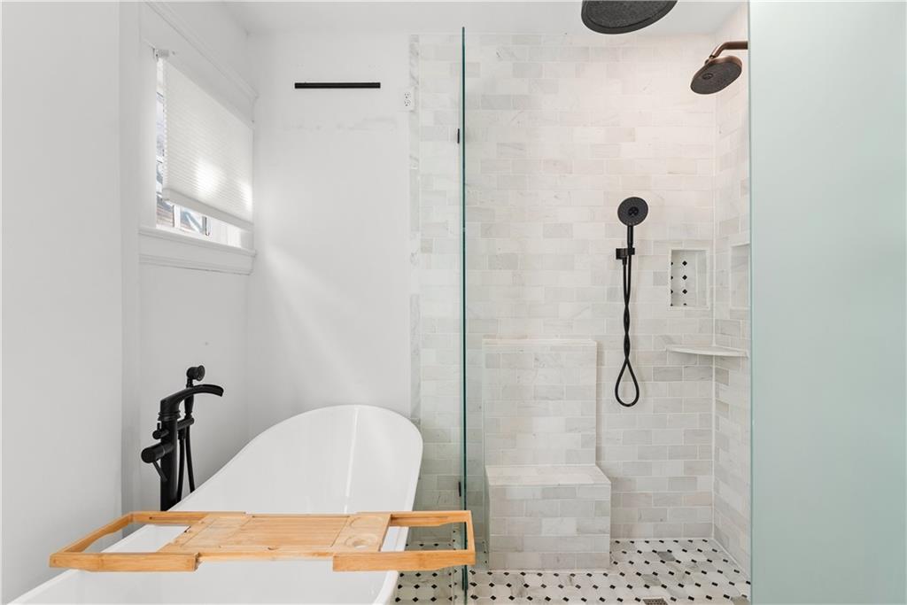 Bathroom with a freestanding soaking tub beside a tiled walk-in shower with a built-in bench.