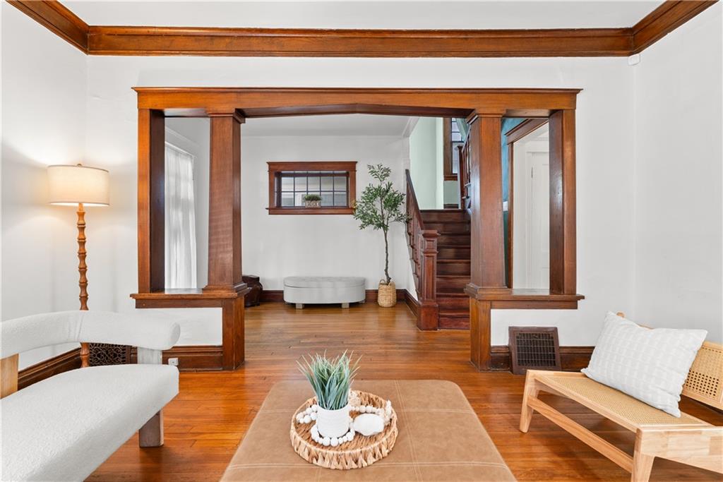 Living room with hardwood floors, dark wood trim, and a staircase beyond the seating area.
