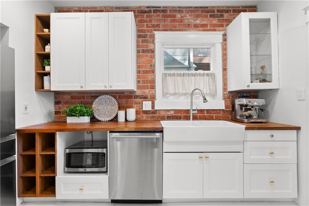 Kitchen with a farmhouse sink, red brick backsplash, and butcher-block countertops.