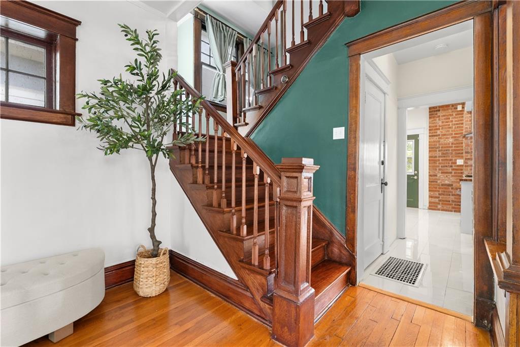 Entryway with a curved wooden staircase, teal wall, and hardwood floors.
