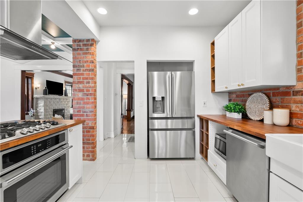 Kitchen with stainless steel appliances, wood countertops, and exposed brick accents.