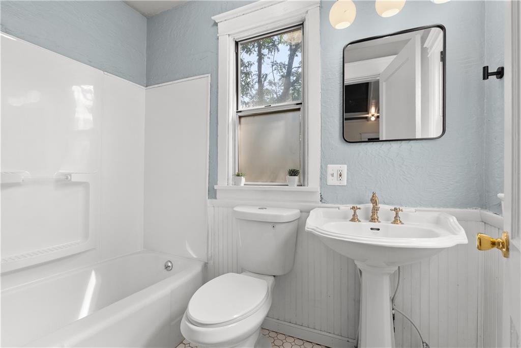 Bathroom with a white bathtub, pedestal sink, and pale blue walls.