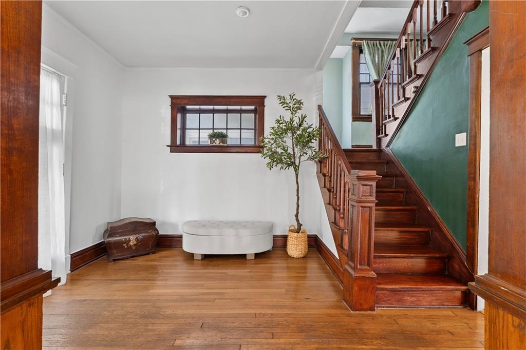 Entryway with a dark wood staircase, green wall, hardwood floors, and a small window.