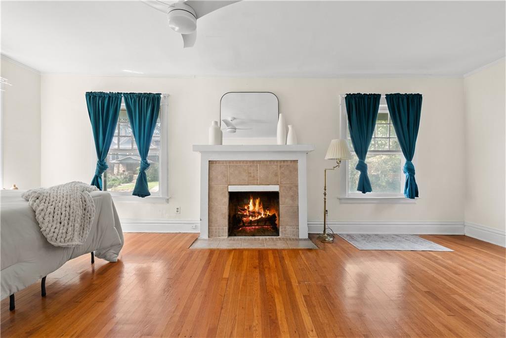Bedroom with a lit tiled fireplace, teal curtains, and hardwood floors.