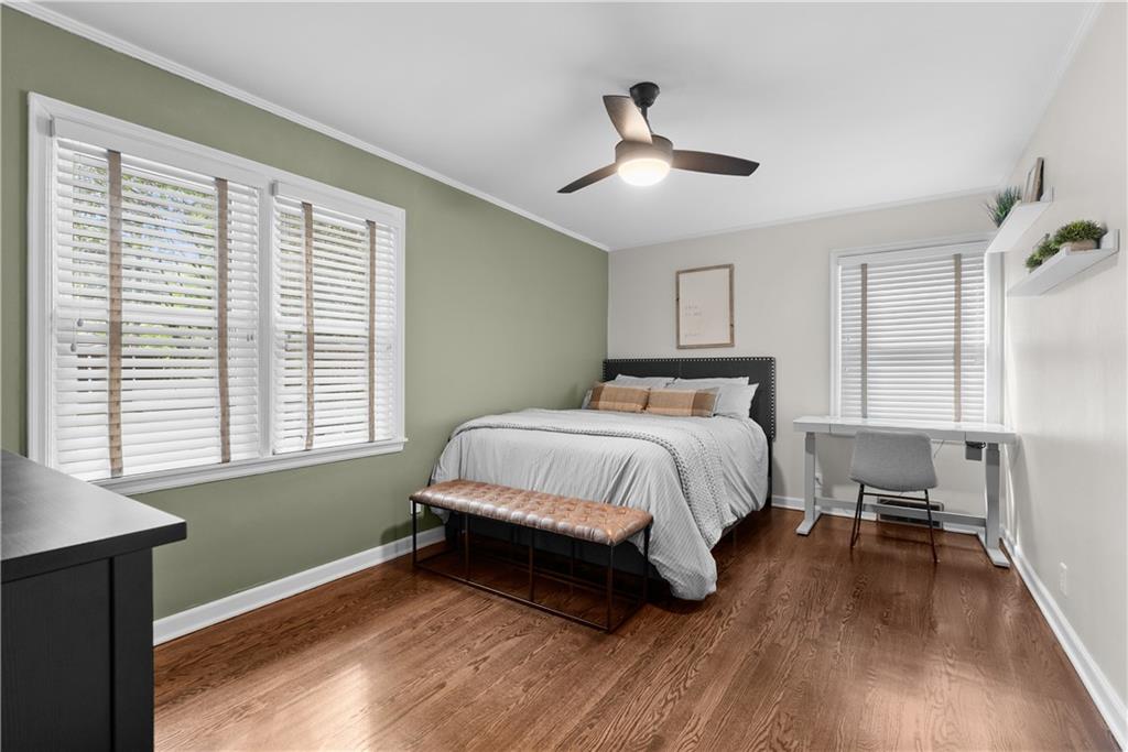 Bedroom with a green accent wall, shuttered windows, a bed, and warm wood flooring.